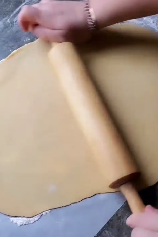 The Best Rusian Honey Cake rolling dough with rolling pin on a black countertop