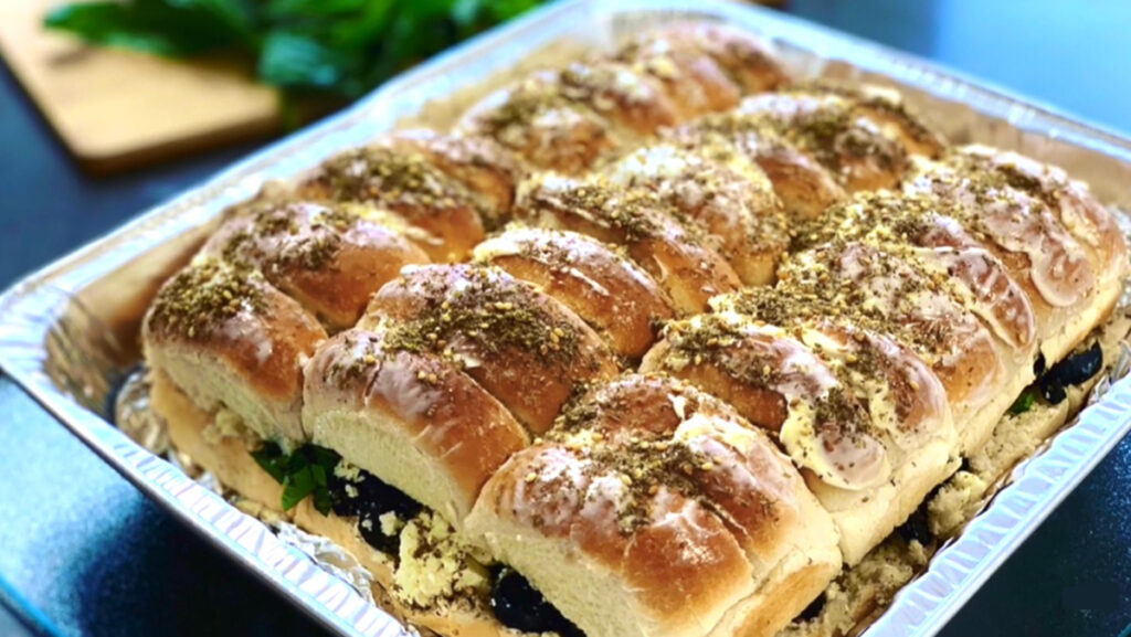 Feta and Olive Pull apart Buns in a silver tin with greenery in background on a black countertop