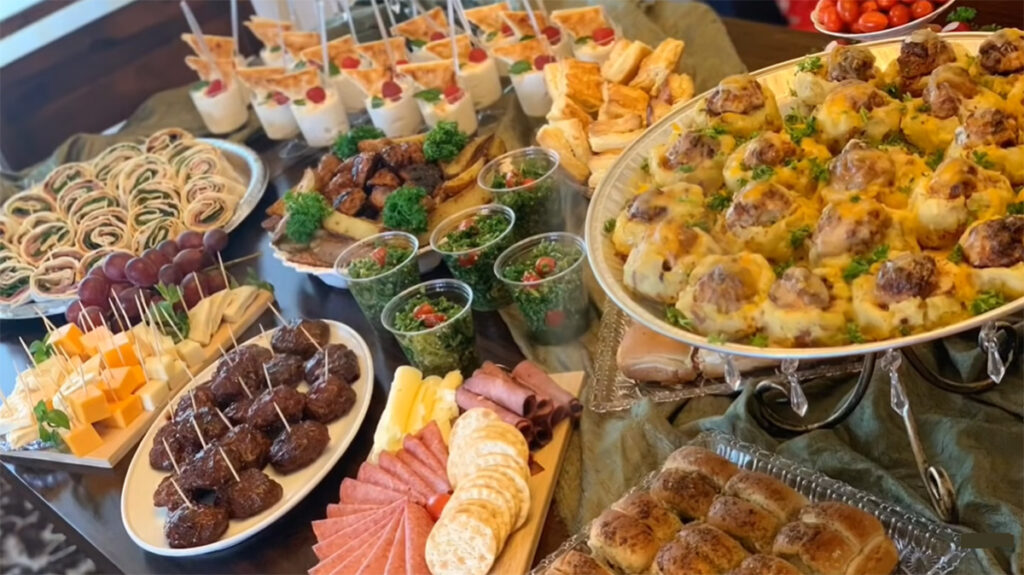 The Best Party Buffet Food Recipe Ideas Tabbule, potato meatballs, cheese puff pastry, meatballs, dessert cups, potato wedges with a green table cloth accenting table