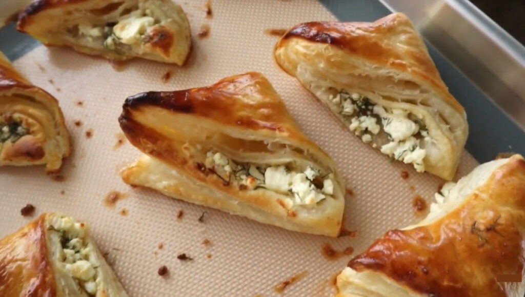 Buttery Cheese Puff Pastry Bites - Borek on a baking pan with a rubber mat baking sheet.