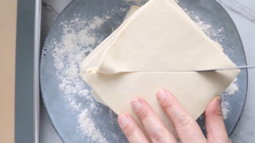 Puff pastry dough on a blue plate with flour on plate.