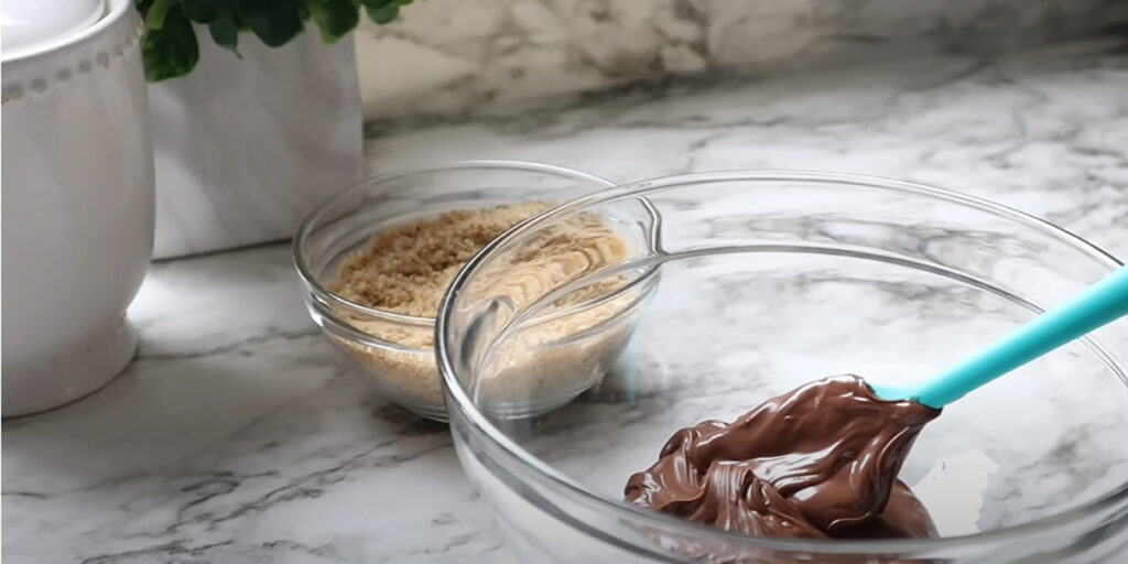 Nutella Walnut Puff Pastry Dessert with a glass bowl of Nutella and crushed walnuts on white coutertop.