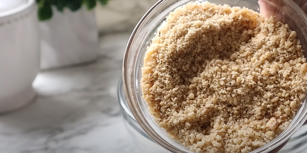 Nutella Walnut Puff Pastry Dessert with a glass bowl of crushed walnuts on a white countertop.