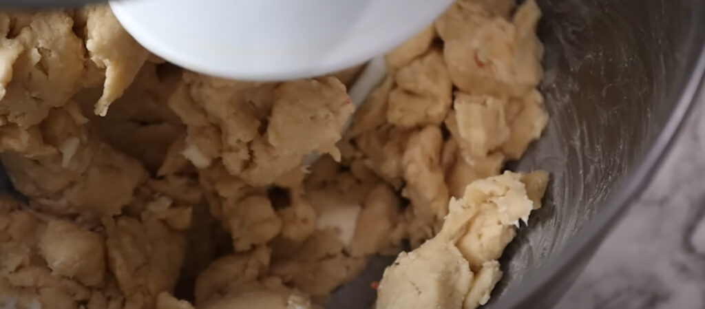 Blueberry Danish Twists mixed dough in a mixing bowl attached to an electric mixer on a white countertop.