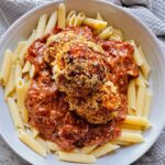 Cajun Chicken Meatball Pasta in a white pasta bowl with a grey towel around the plate as accent decor.