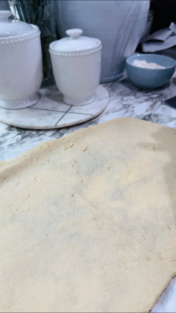 Walnut Roll Pastry - Rolled out dough on a white countertop with white canisters in the back