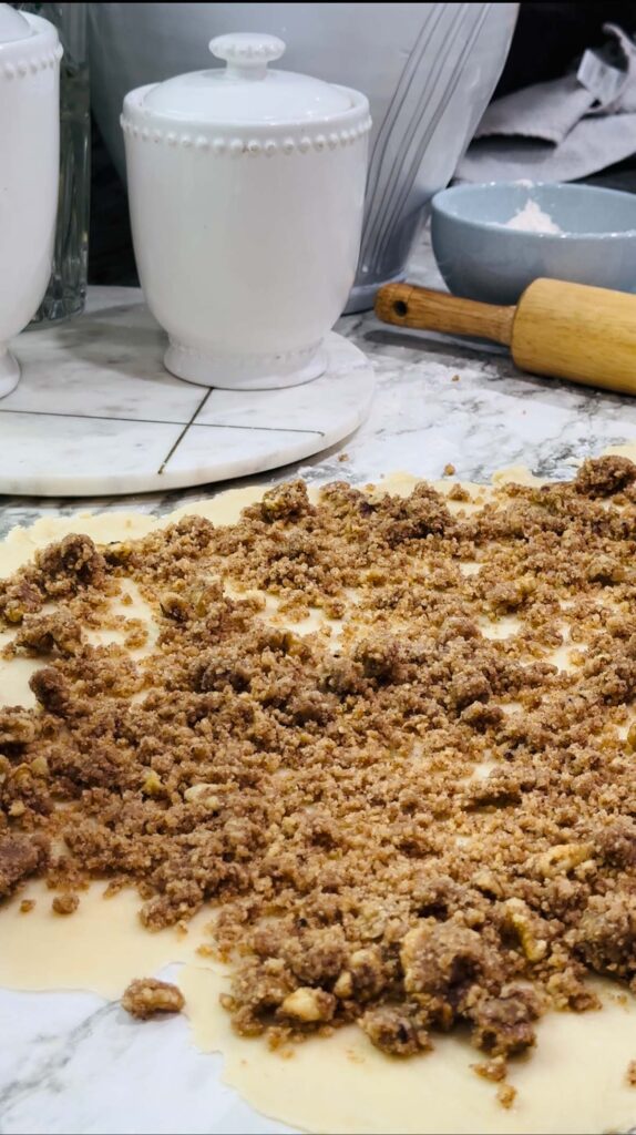 Walnut Roll Pastry - Rolled out dough walnut spread ontop on a white countertop with white canisters in the back