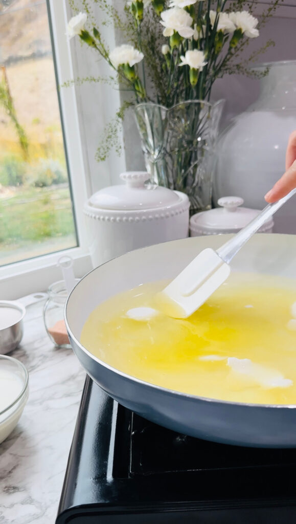 Walnut Roll Pastry with a blue and white cooking pan melting crisco shortening with a glass bowl of oil on a white countertop in front of a kitchen window.