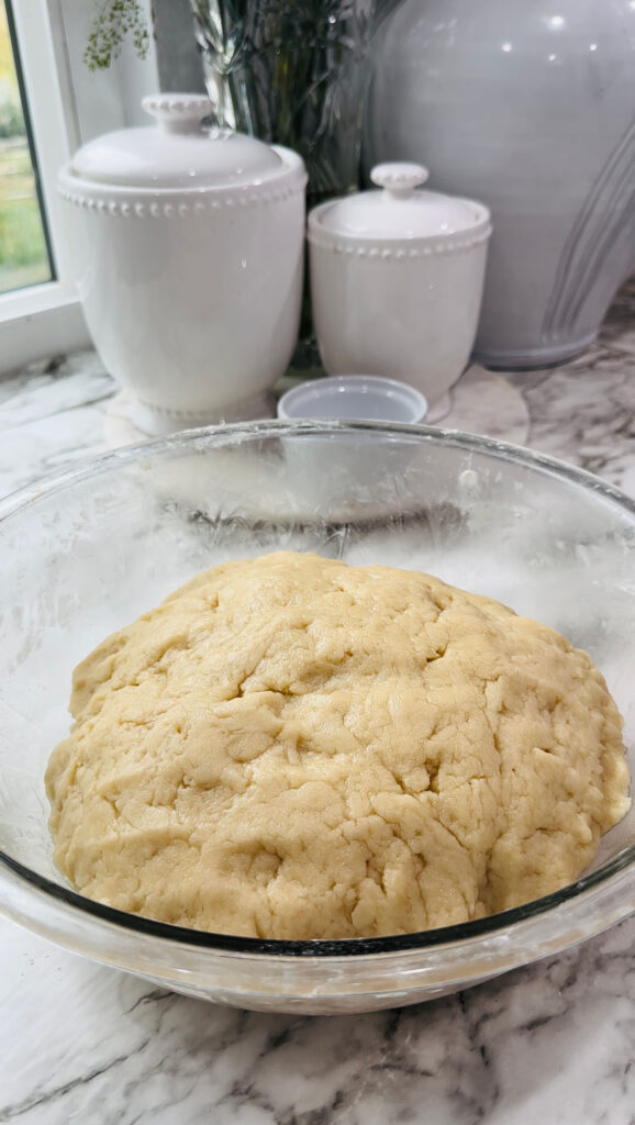 Walnut Roll Pastry - Glass bowl with dough with white canisters on a white granite countertop