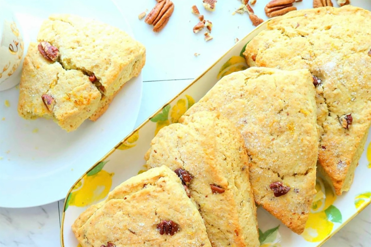 Lemon Tahini Scones on a lemon dish with crushed nuts on a white tabletop.