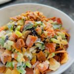 Cucumber tomato pita salad in a while bowl on a black countertop