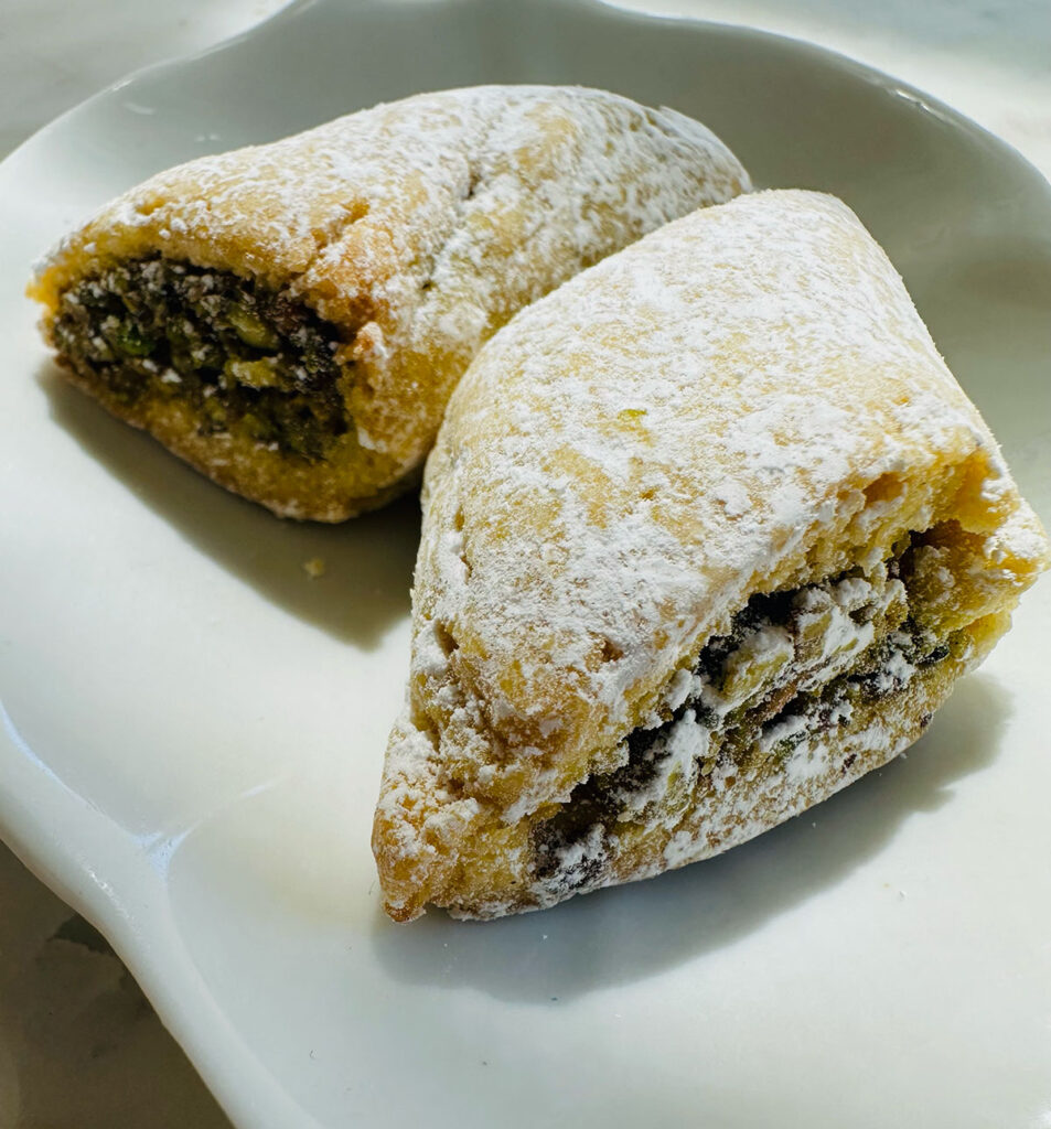 Ma'amoul Cookie Hand Made with Pistachios in center with powdered sugar sprinkled ontop cut into small triangle shapes