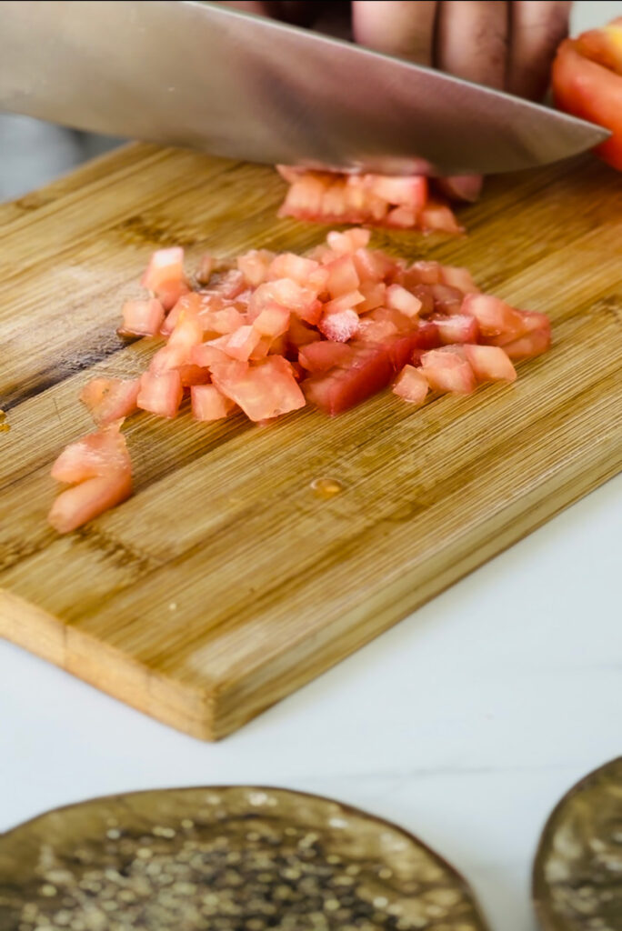 Cleaned and skinned tomatoes diced and cut into cubes on a wooden chopping board.