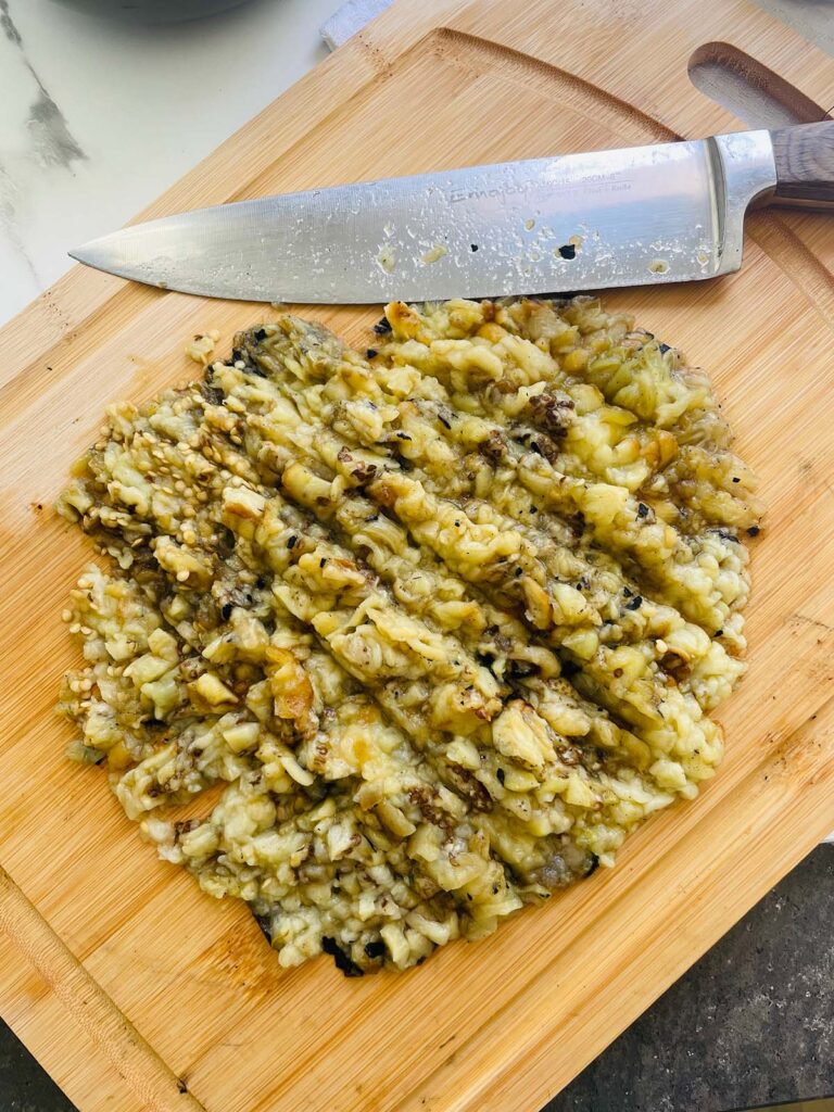 Babaganoush Recipe - roasted chopped eggplants on the counter on the chopping board with a knife