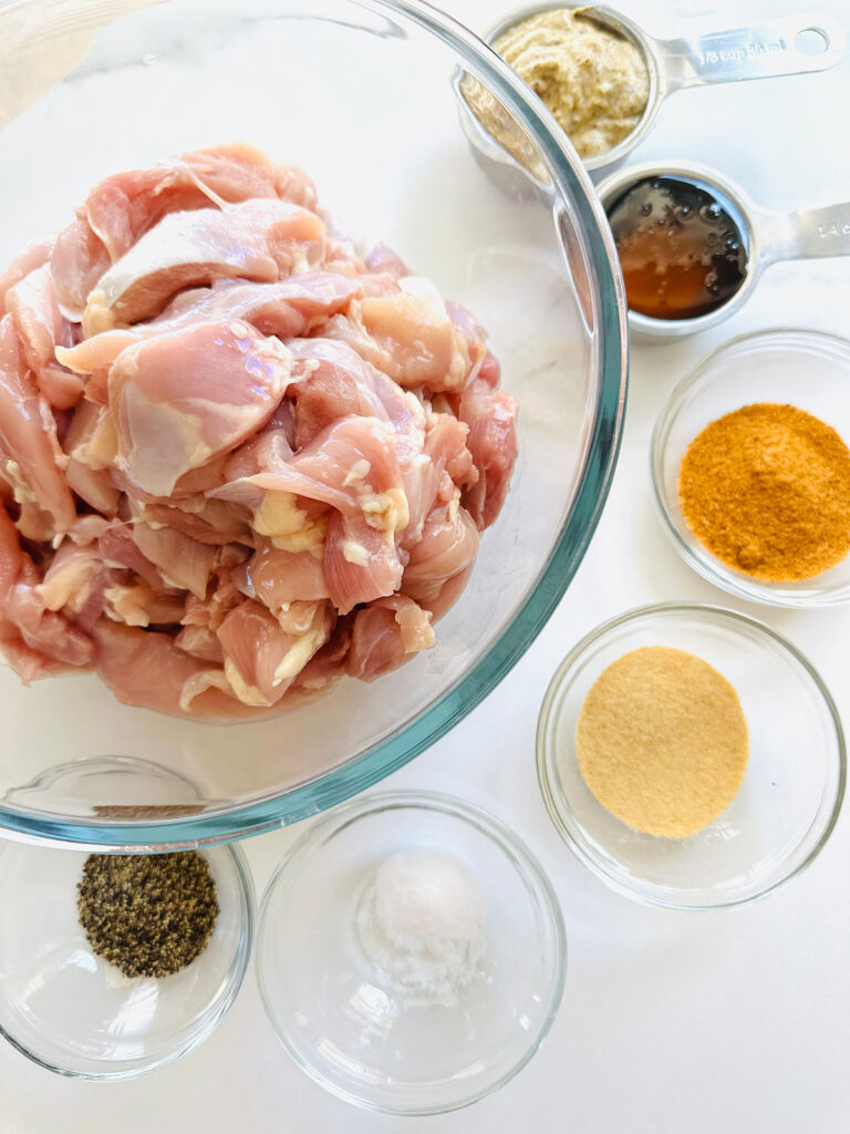 Honey Mustard Chicken with Pinapple Salad w/ Orzo Rice chicken in a glass bowl with glass bowls of seasonings around lage bowl of chicken.
