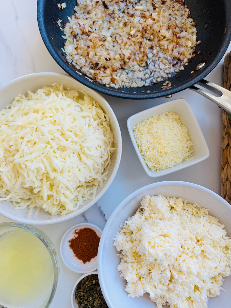 Mediterranean Meat & Cheese Savory Rolls- white bowl with three-different cheeses with chilli powder and a pan of sauted onions.