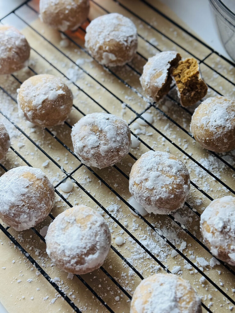 Spiced Holiday Pryaniki Cookies - Ginger Cookies- frosted cookies on a black cooling rack with parchment paper underneath with a broken cookie on the top right.