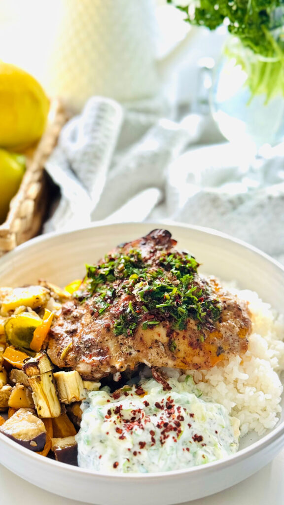 Aleppo Chicken Veggie Rice Bowl with Aleppo Chili Oil - in w white platter with a grey towl and with fresh lemons in background.